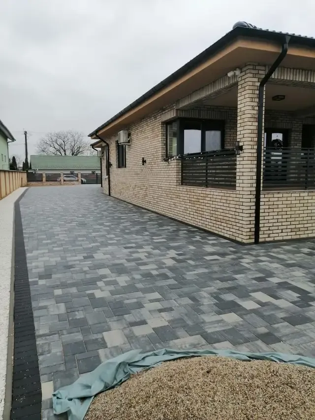 Locuință cu fațadă din cărămidă aparentă și alei pavate