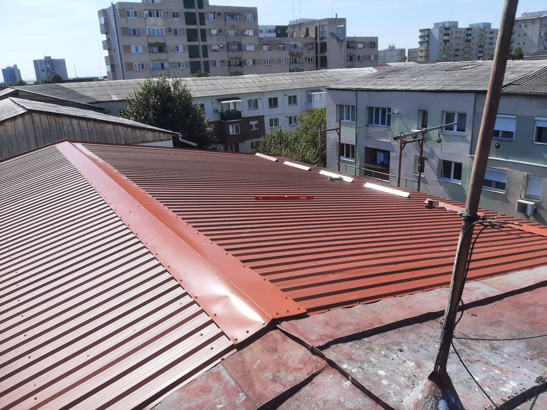 Învelitoare nouă din tablă cutată roșie montată pe un acoperiș