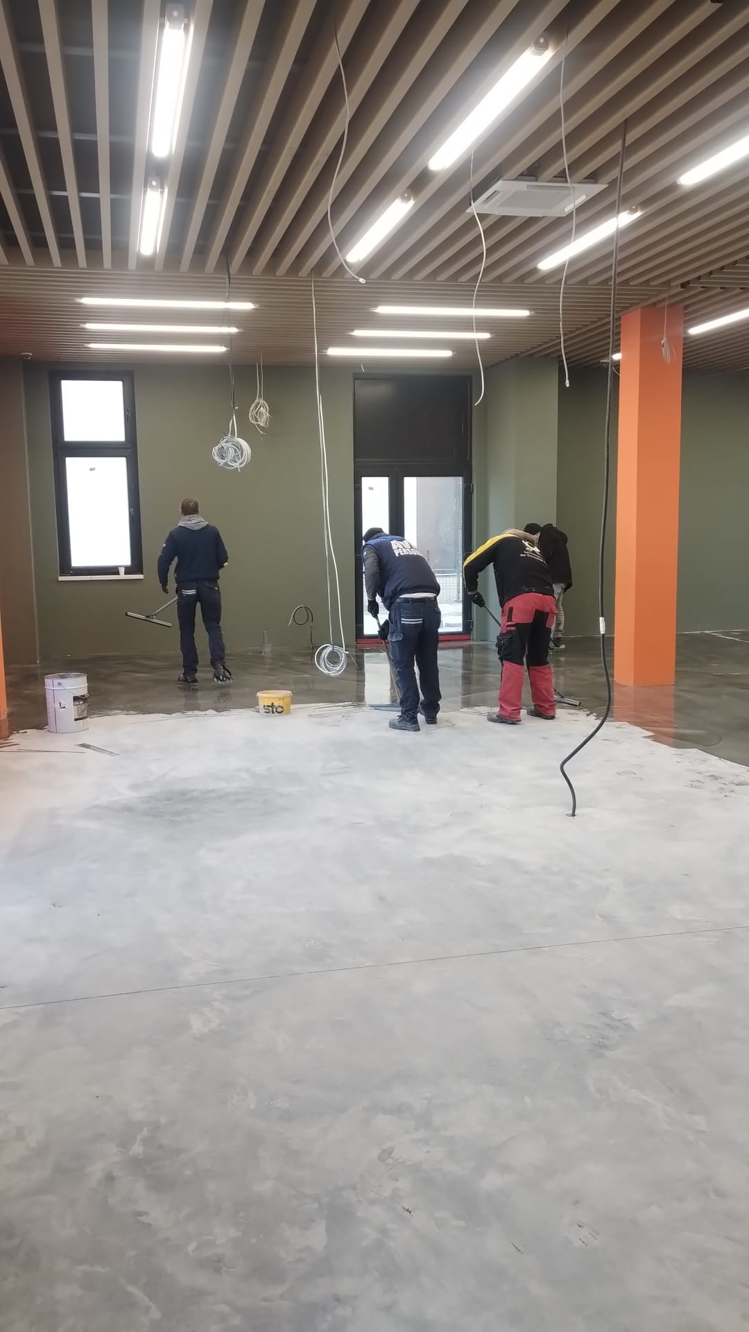 Echipa STO aplicând pardoseală autonivelantă într-un spațiu comercial